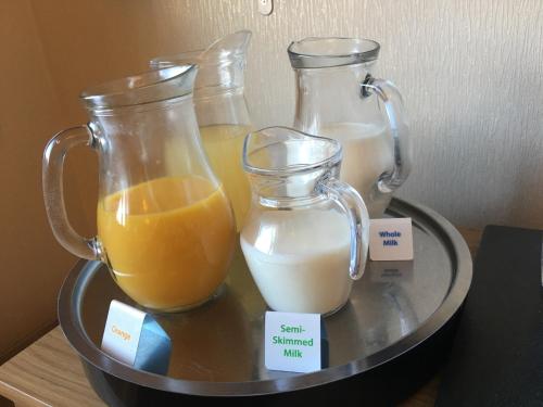 drie glazen bakjes met sinaasappelsap en melk op een dienblad bij Rothay House in Ambleside