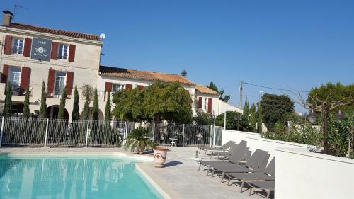 a swimming pool with lounge chairs and a building at Hotel Le Mas Saint Joseph in Saint-Rémy-de-Provence