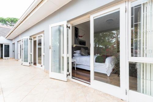Pokój z przesuwnymi szklanymi drzwiami prowadzącymi do sypialni w obiekcie Whispering Palms w mieście Port Elizabeth