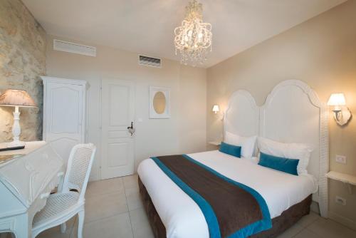 a bedroom with a bed and a desk and a chandelier at Hotel Le Mas Saint Joseph in Saint-Rémy-de-Provence