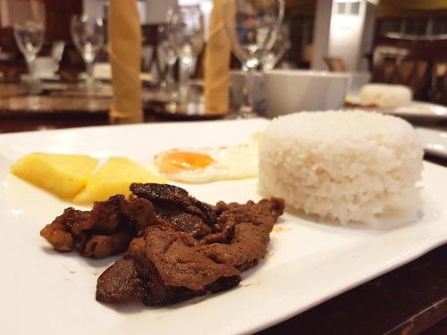 a plate of food with rice and meat on a table at Stay Amare Villa Maria 1 in Bacolod