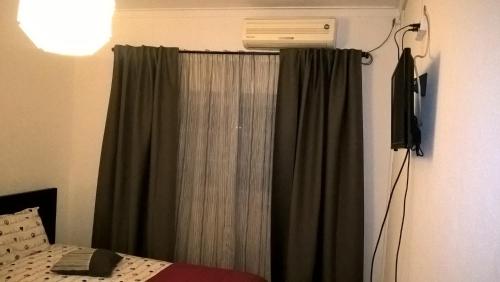 a bedroom with a window with a green curtain at Casa do Limoeiro in Quinta do Conde
