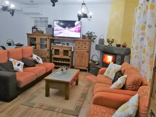 a living room with orange couches and a tv at Casal do Vulcão in Capelo