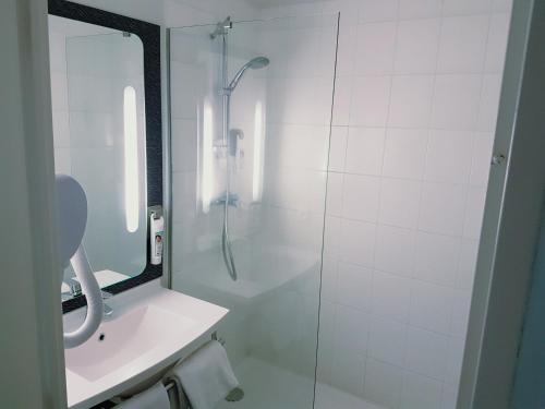 a bathroom with a shower and a sink and a mirror at ibis Clermont Ferrand Nord Riom in Riom