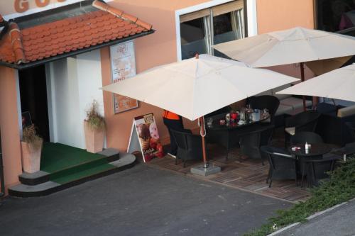 a restaurant with tables and umbrellas outside of a building at Guesthouse ob Sotočju Budič in Brežice