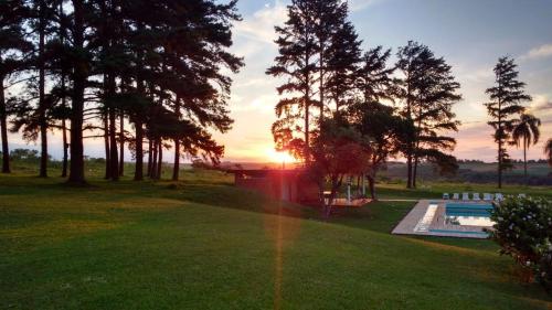 um pôr-do-sol sobre um quintal com piscina e árvores em Hotel Pousada La Vierro em Ponta Grossa
