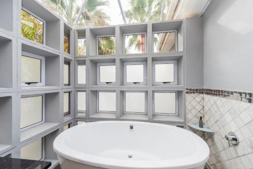 a bathroom with a white tub and windows at Whispering Palms in Port Elizabeth