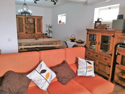 an orange couch with pillows in a living room at Casal do Vulcão in Capelo