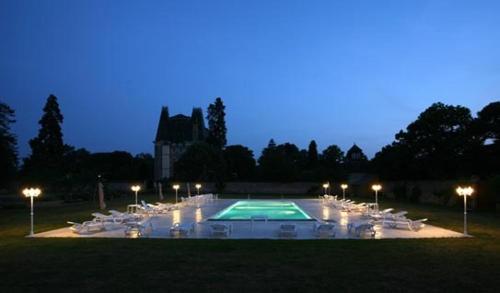 - une piscine avec des chaises blanches et des lumières la nuit dans l'établissement Château de Montbraye, à Parigné-lʼÉvêque