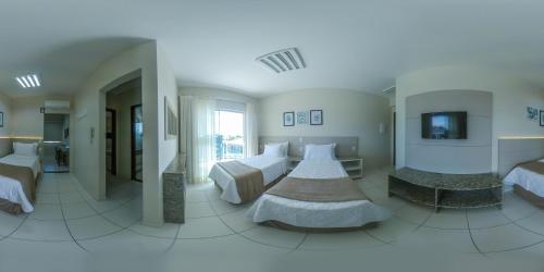 a hotel room with two beds and a television at Pousada Doluar in Penha