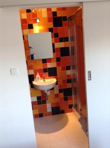 a bathroom with a sink and a tiled wall at Lux Hostel - z prywatnymi łazienkami in Gdynia