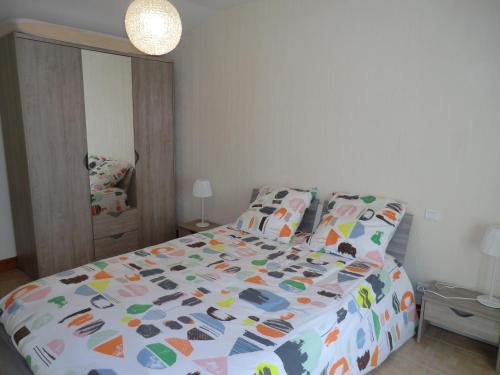 a bedroom with a bed with a colorful comforter at Le Refuge in Champagné-Saint-Hilaire