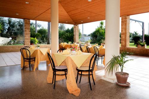 a restaurant with tables and chairs with yellow table cloth at Hotel Salento in Specchia