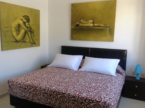 a bedroom with a bed with two paintings on the wall at 8villa in St Julian's