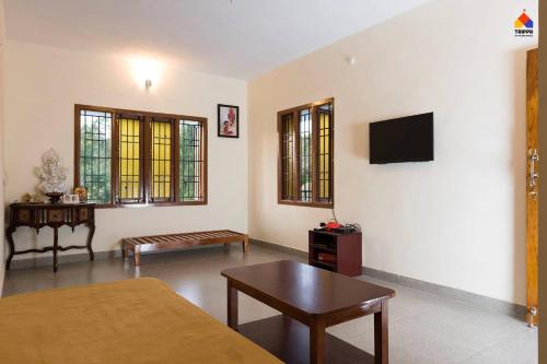 a living room with a couch and a tv on the wall at Trippr Kodaikanal Backpacker Hostel in Kodaikānāl