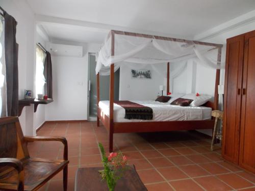 a bedroom with a canopy bed and a chair at Le Logis de Kep in Kep