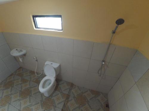 a bathroom with a toilet and a window and a shower at Ila Homestay in Senaru