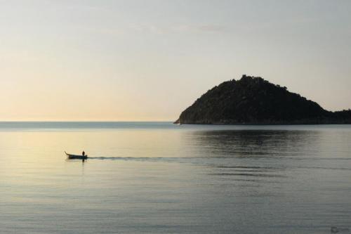 a person in a boat in the water with an island at Residence Sole in Albenga