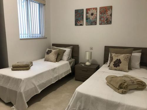 1 dormitorio con 2 camas y mesa con lámpara en Azure Cottage, en Żebbuġ