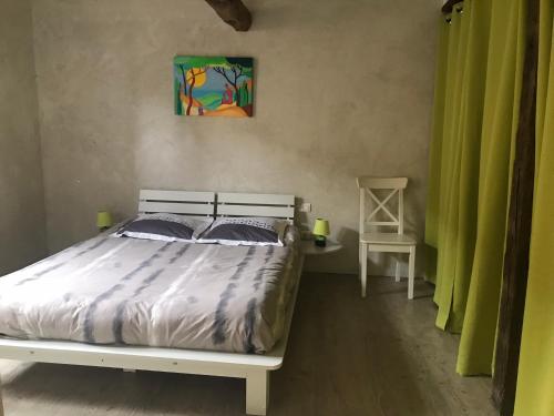 ein Schlafzimmer mit einem weißen Bett und einem Stuhl in der Unterkunft La Maison De Chloe in Senouillac