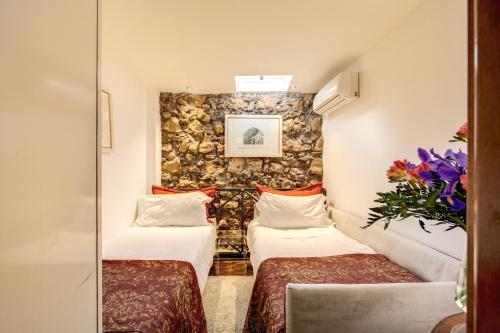 two beds in a room with a stone wall at Pantheonview - Luxury Suites in Rome