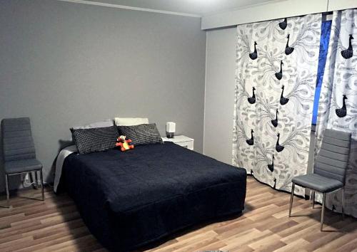 a bedroom with a black bed and two chairs at Villa Porkka in Kuusamo
