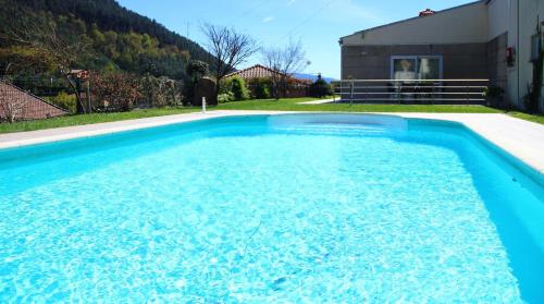 a large blue swimming pool in front of a house at Casinhas do Gerês in Geres