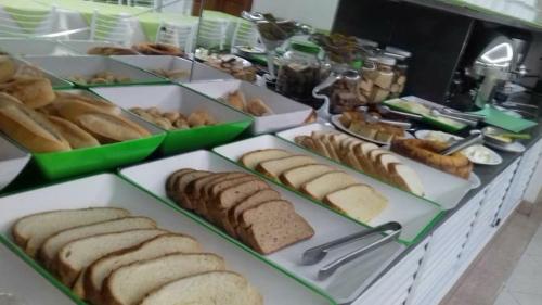 a buffet of bread and pastries on plates on a counter at Hotel Lopes in Cubatão