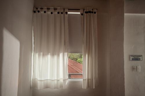 a window with a white curtain in a room at HOTEL LA SELVA Reserva in La Vega