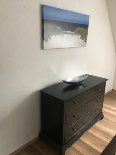 a black dresser in a room with a painting on the wall at Hanse Hotel Buxtehude in Buxtehude