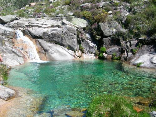 a pool of water in front of a waterfall at Casinhas do Gerês in Geres