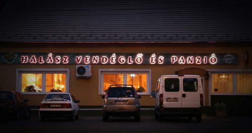 two cars parked in front of a restaurant at night at Halász Airport Panzio in Vecsés