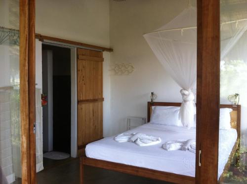 a bedroom with a bed with white sheets and a window at Casa da Gwen in Jericoacoara