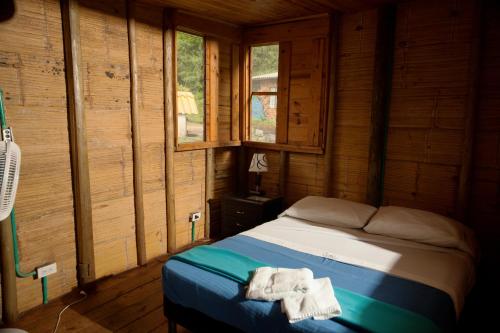 a bed in a wooden room with towels on it at HOTEL LA SELVA Reserva in La Vega