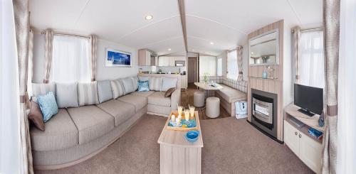 a living room with a couch and a tv at Sunnyglen Holiday Park in Saundersfoot