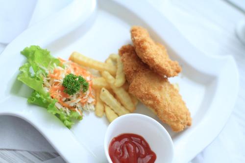 a plate of food with french fries and ketchup at Tjokro Hotel Pekanbaru in Pekanbaru