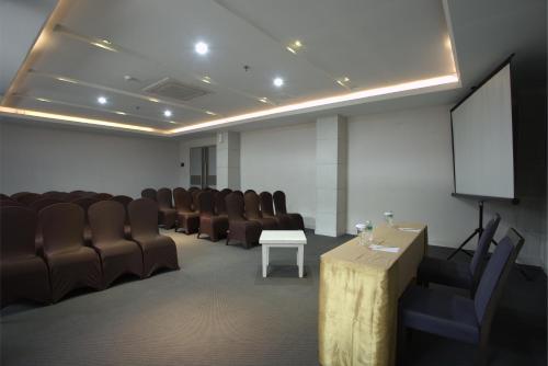 a conference room with brown chairs and a screen at Tjokro Hotel Pekanbaru in Pekanbaru