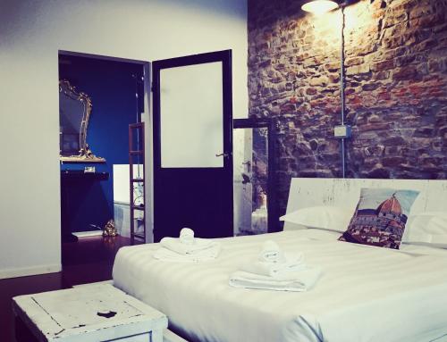 a bedroom with a large white bed with a brick wall at Velvet Loft - Santo Spirito Apartment in Florence