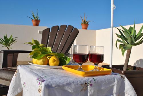 un tavolo con due bicchieri di vino e un piatto di frutta di Casa Frida a San Vito lo Capo