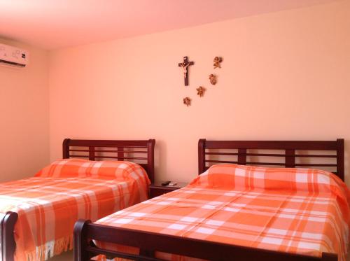 two beds in a room with a cross on the wall at Apartamentos Cartagena in Cartagena de Indias