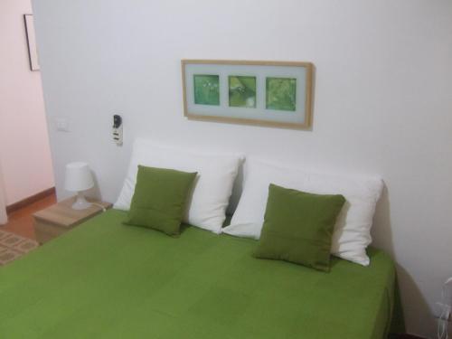 een slaapkamer met een groen bed en 2 groene kussens bij Casa Vacanze Helena in Cava dʼAliga