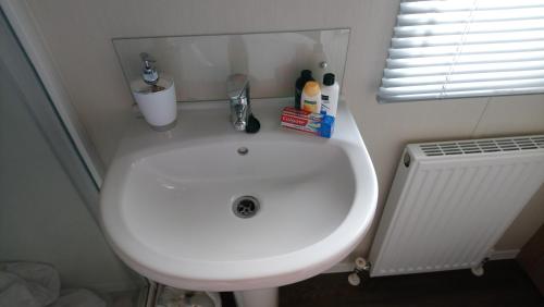 Un lavabo blanco en un baño con ventana. en Bude Caravan Caromax - Families and Couples Only, en Bude