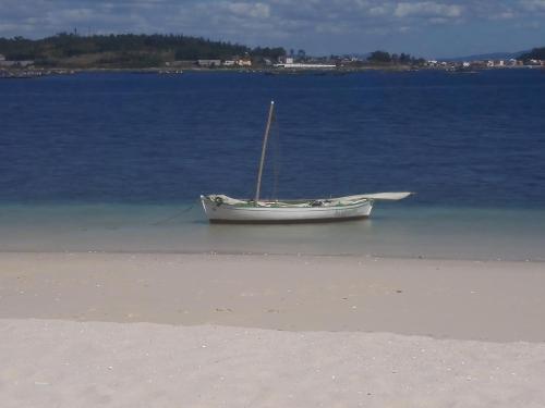 a boat sitting in the water on the beach at Casa Guillan Illa de Arousa in Isla de Arosa