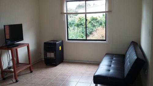 sala de estar con sofá y TV en Departamentos Arlenne, en Valdivia