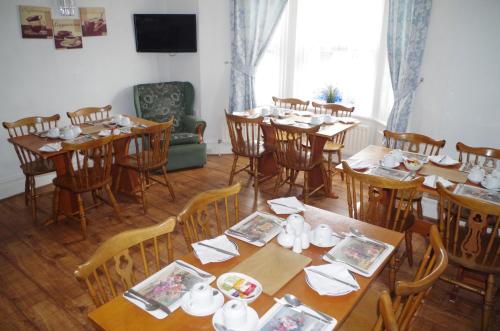 una sala da pranzo con tavoli e sedie e piatti di Abbey Lodge Guest House a Southampton