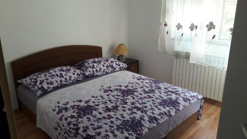 Un dormitorio con una cama con una manta de flores y una ventana en Analeo en Šibenik