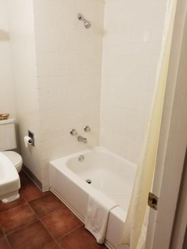 a white bathroom with a tub and a toilet at Bridge Street Inn in Baker City