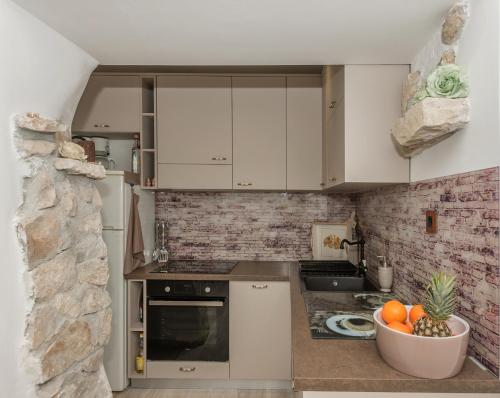 uma cozinha com armários brancos e uma taça de fruta em Apartman Teta Jadre em Makarska