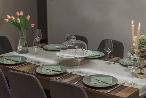 a table with green plates and wine glasses and candles at Apartman Teta Jadre in Makarska