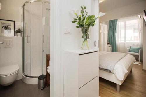 uma casa de banho branca com uma cama e um vaso de flores em Apartmani Leo-Marin em Makarska